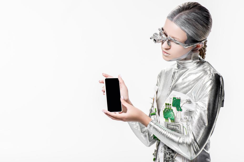 Silberroboter blickt auf Smartphone mit leerem Bildschirm isoliert auf weißem, zukünftigem Technologiekonzept - Foto, Bild
