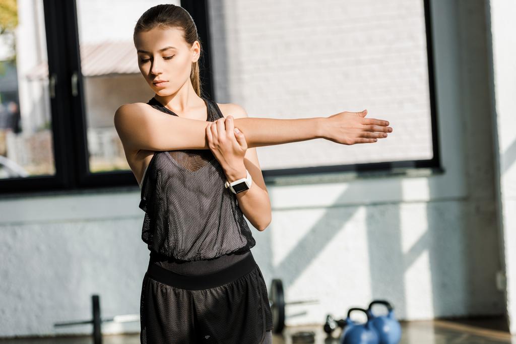 красивая спортсменка делает упражнения перед тренировкой в тренажерном зале
 - Фото, изображение