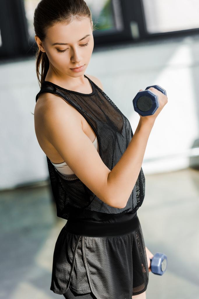 portrait of beautiful sportswoman training with dumbbells at sports center - Photo, Image