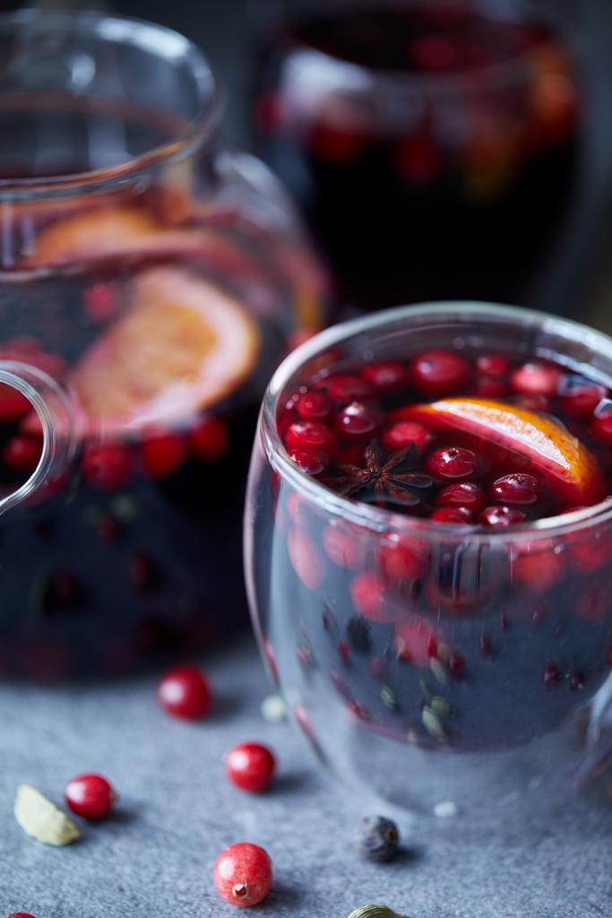 κοντινό πλάνο, νόστιμο σπιτικό mulled κρασί με cranberries και πορτοκαλί στο τραπέζι στην κουζίνα - Φωτογραφία, εικόνα