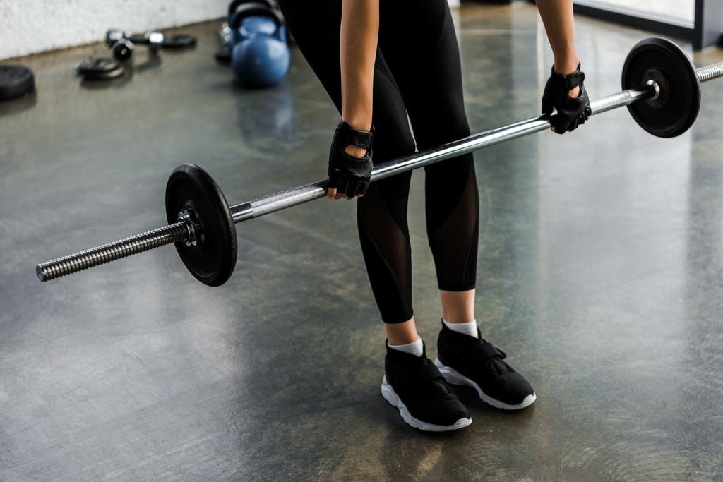 baixa seção de esportista em treinamento luvas de levantamento de peso com barra no ginásio
 - Foto, Imagem
