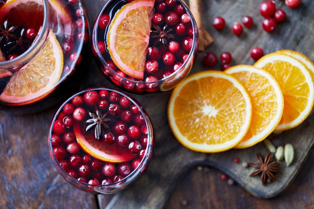 elevated view of homemade mulled wine with cranberries and oranges on table in kitchen - Photo, Image