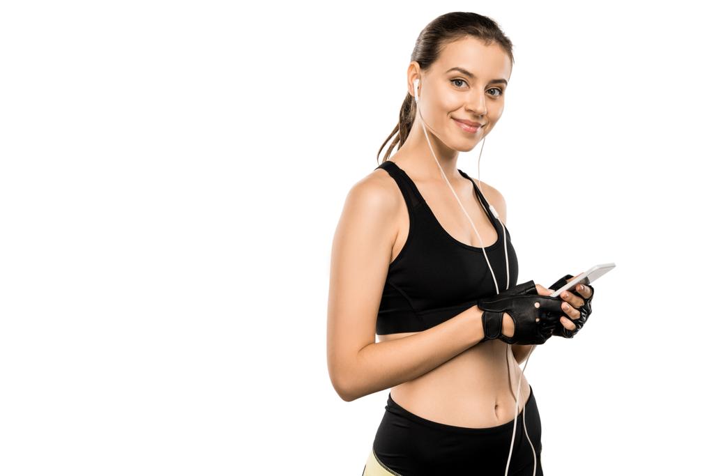 приваблива спортсменка в важких рукавичках та навушниках, використовуючи смартфон ізольовано на білому
 - Фото, зображення