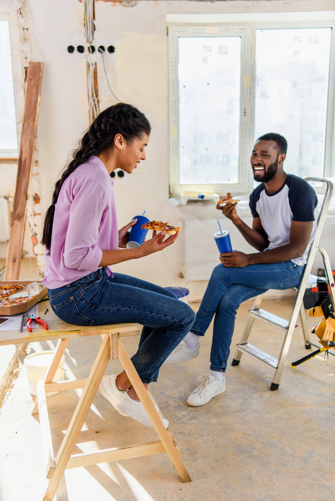 счастливая пара с газировкой и пиццей расслабляющий во время ремонта дома
 - Фото, изображение