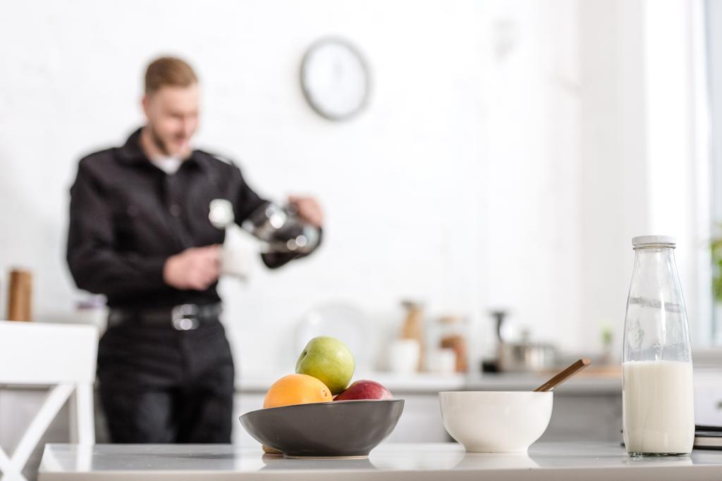 пляшка молока, миска з фруктів на кухонному столі та поліцейський на фоні
 - Фото, зображення
