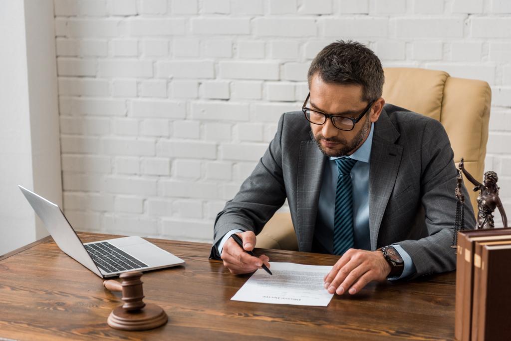 високий кут зору концентрованого адвоката чоловічої статі в окулярах, що працюють з документом в офісі
  - Фото, зображення
