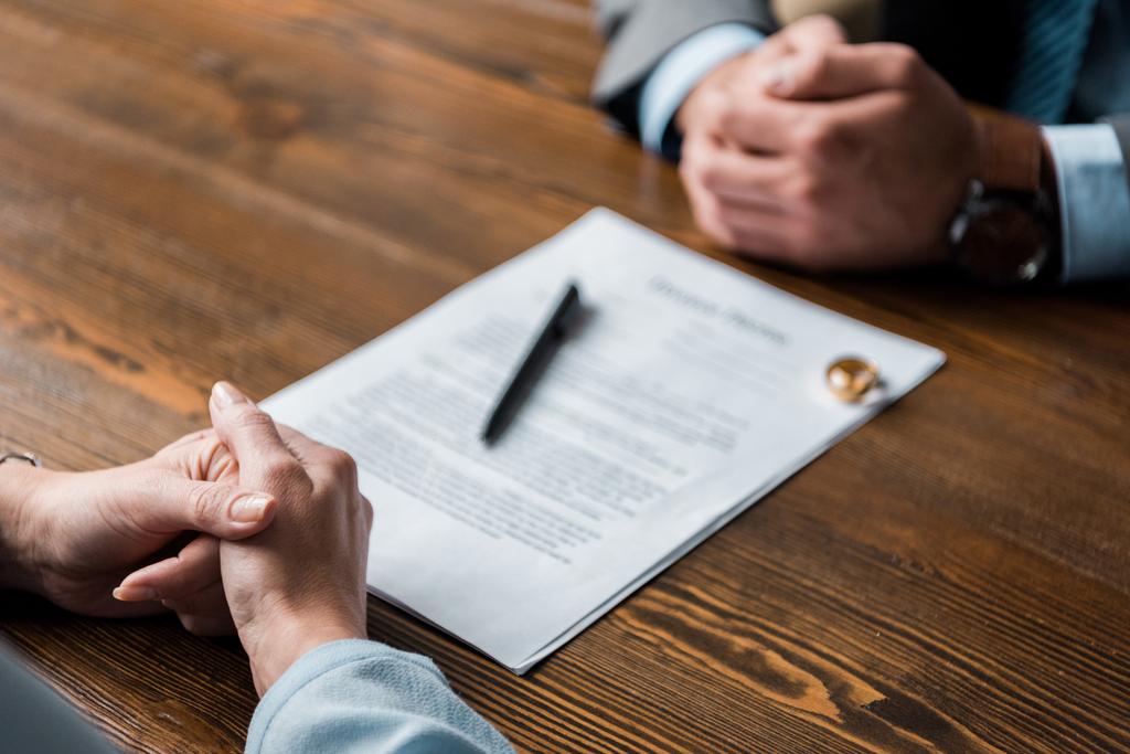 частичный взгляд на адвоката и клиента, сидящего за столом с постановлением о разводе и обручальными кольцами
  - Фото, изображение
