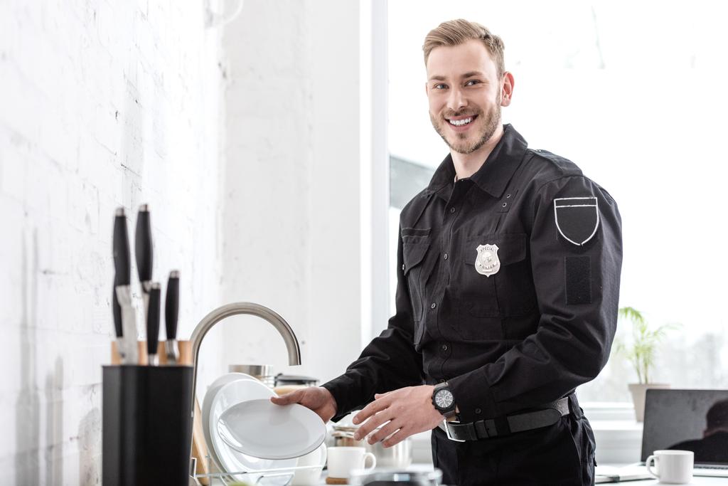 schöner Polizist spült Geschirr in der Küche - Foto, Bild