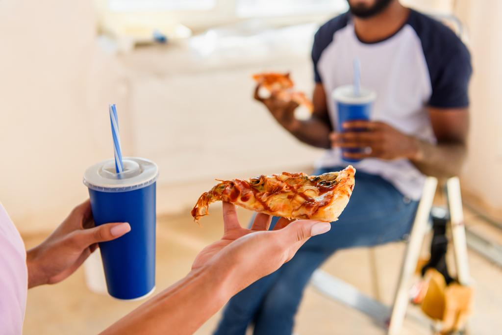 обрезанное изображение пары, обедающей с пиццей и содовой во время ремонта
 - Фото, изображение