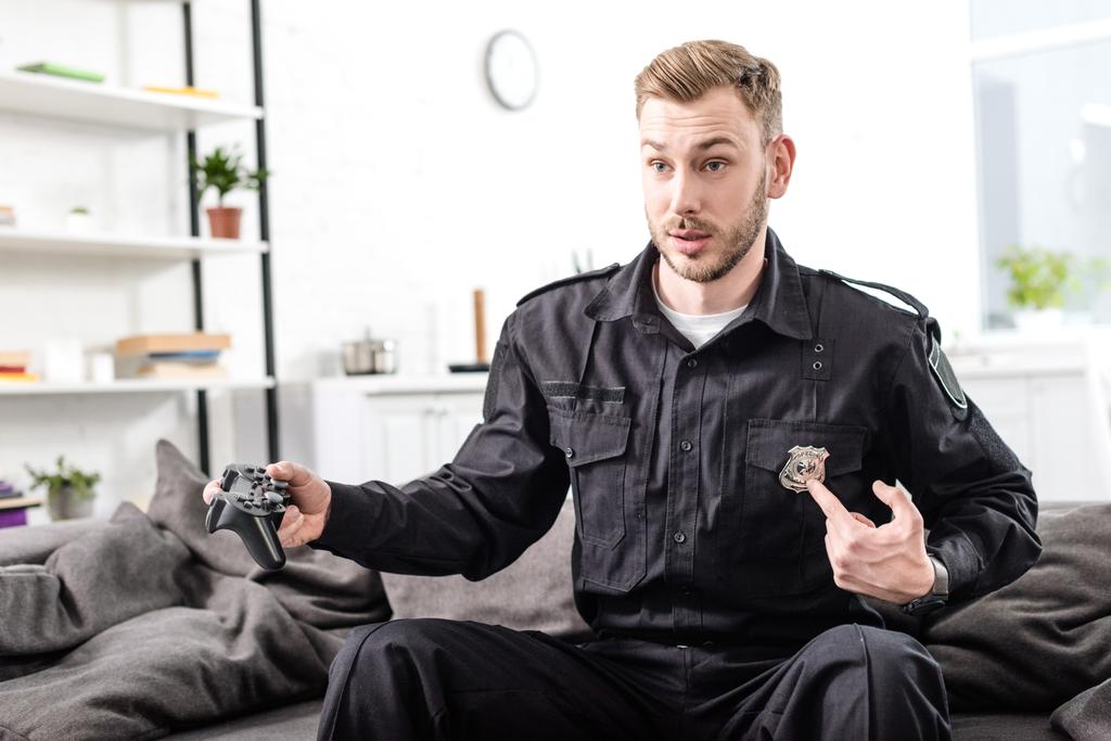 surprised police officer playing video game and pointing at police badge - Photo, Image