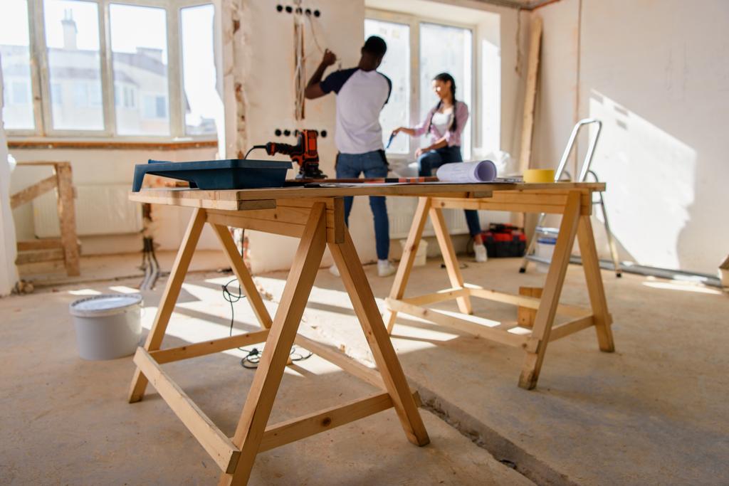 messa a fuoco selettiva di tavolo in legno con strumenti e coppia fare ristrutturazione dietro a casa
 - Foto, immagini