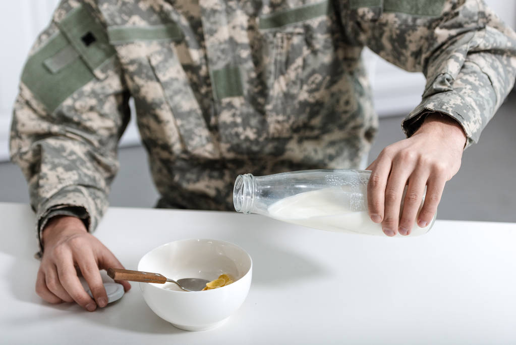 vista recortada del militar vertiendo leche en un tazón con copos de maíz
 - Foto, imagen