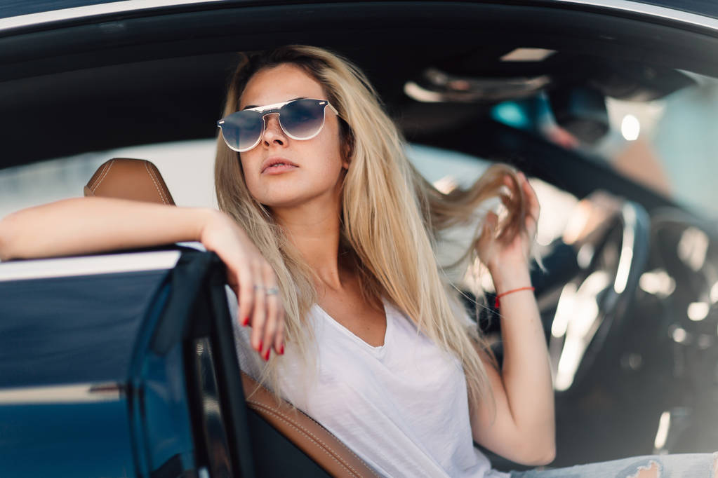 Portrait of blonde in sunglasses sitting in car - Photo, Image