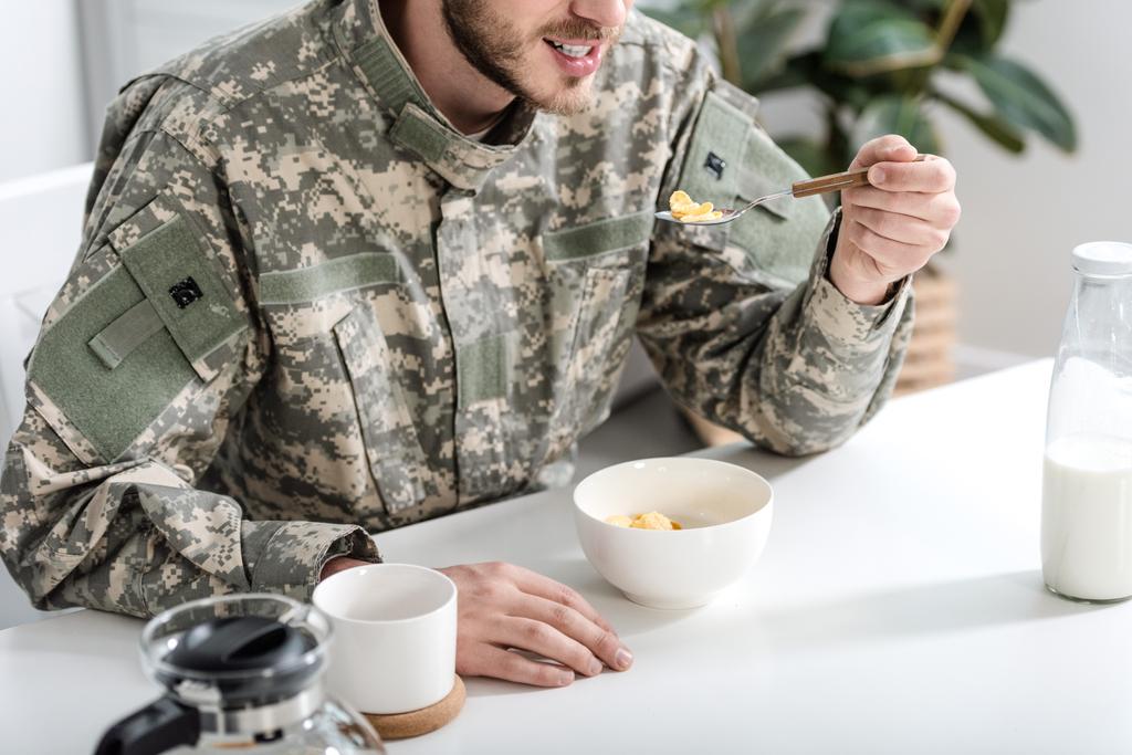 vista recortada del hombre en uniforme de camuflaje desayunando por la mañana
 - Foto, imagen