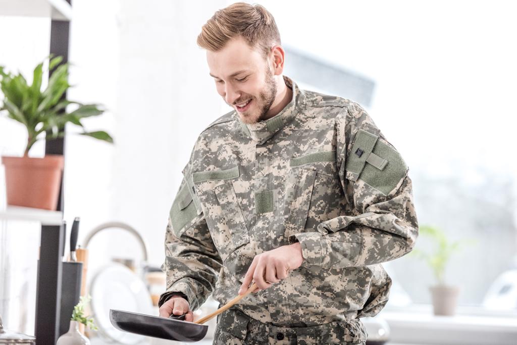 hymyilevä armeija sotilas ruoanlaitto pannulla keittiössä
  - Valokuva, kuva