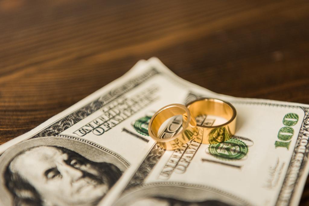 Close-up shot van contant geld en trouwringen op houten tafel - Foto, afbeelding