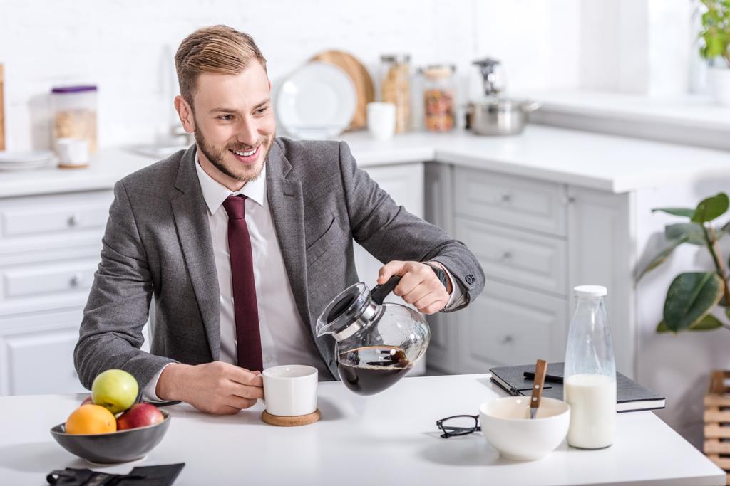 красивий бізнесмен наливає фільтровану каву в чашку за кухонним столом
 - Фото, зображення