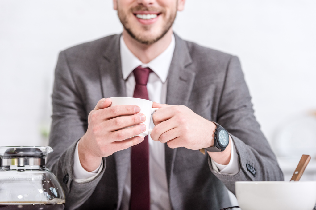 περικοπεί θέα χαμογελώντας επιχειρηματίας πίνοντας καφέ στην κουζίνα - Φωτογραφία, εικόνα