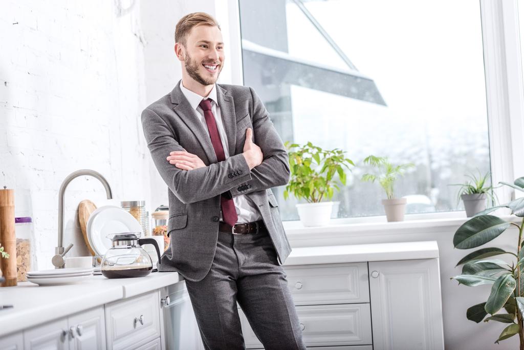 улыбающийся бизнесмен со скрещенными руками на кухне
 - Фото, изображение