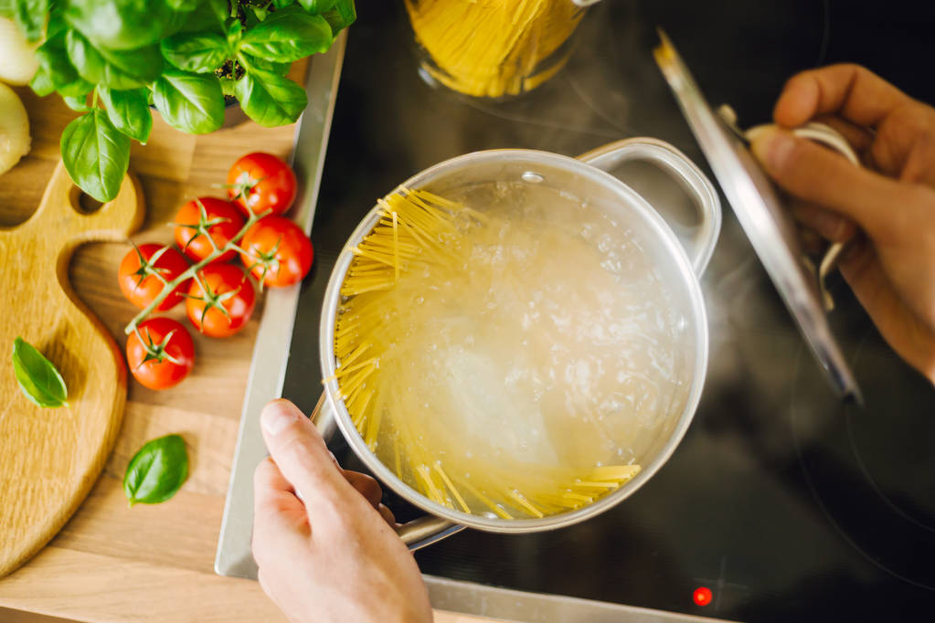 bijgesneden schot van man zelfgemaakte Italiaanse pasta koken - Foto, afbeelding