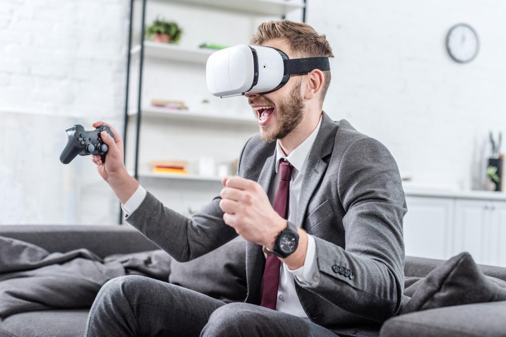 возбужденный бизнесмен в наушниках виртуальной реальности и играет в видеоигры на диване дома
 - Фото, изображение