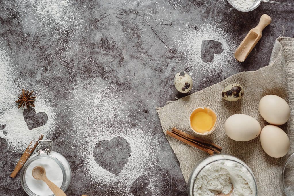 健康なベーキング成分。小麦粉、麺棒、卵、キッチン灰色のキッチン テーブルの上のハートと背景。バレンタインデーの調理用平面図です。コピー スペース. - 写真・画像