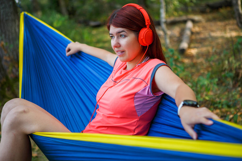 Foto de morena em fones de ouvido ouvindo música enquanto sentado na rede
 - Foto, Imagem