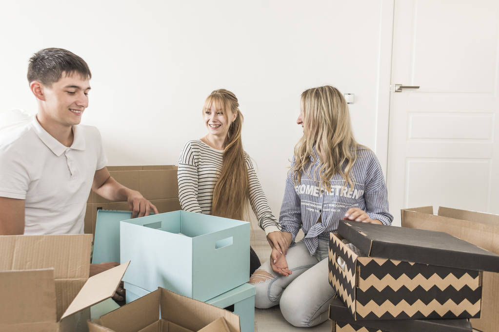 Семья распаковывает картонные коробки в новом доме. переезжаю в новый дом. концепция счастливой семьи и новоселье
 - Фото, изображение