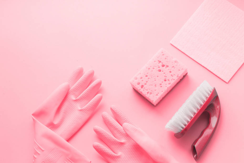 Flat lay Detergentes y accesorios de limpieza y manos de mujer en guantes de goma en color rosa. Servicio de limpieza concepto. Pisos, Vista superior
. - Foto, imagen