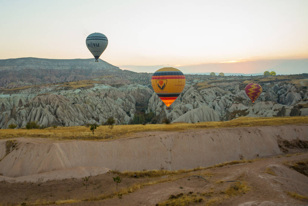 Veel kleurrijke hete lucht ballonnen vlucht boven bergen - panorama van Cappadocië bij zonsopgang. Breed landschap van Goreme vallei in Cappadocië - billboard achtergrond voor uw concept reizen in Turkije. - Foto, afbeelding