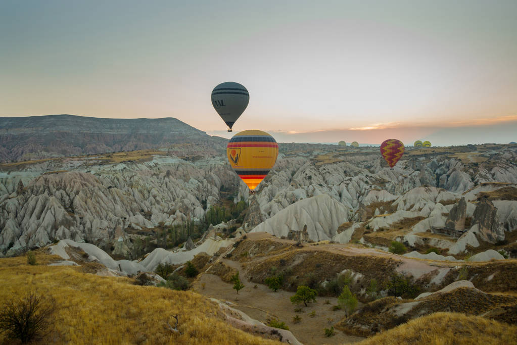 Muitos balões de ar quente coloridos voam acima das montanhas - panorama da Capadócia ao nascer do sol. Ampla paisagem do vale de Goreme na Capadócia - fundo de cartaz para o seu conceito de viagem na Turquia
. - Foto, Imagem