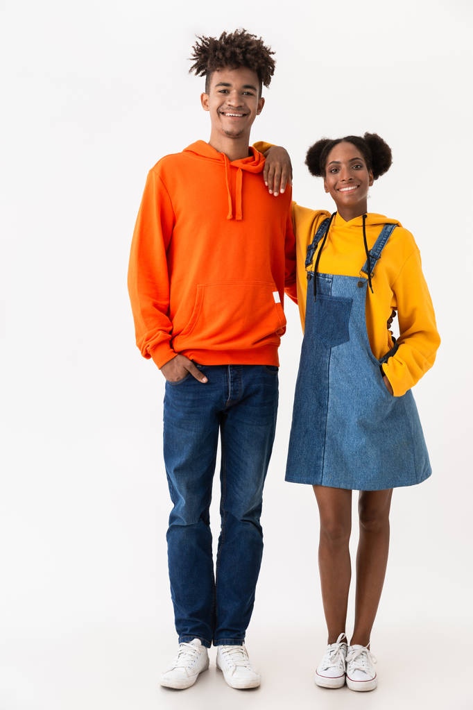 Foto a figura intera di gioioso fratello e sorella afroamericano in abiti colorati sorridenti mentre stanno insieme isolati su sfondo bianco
 - Foto, immagini