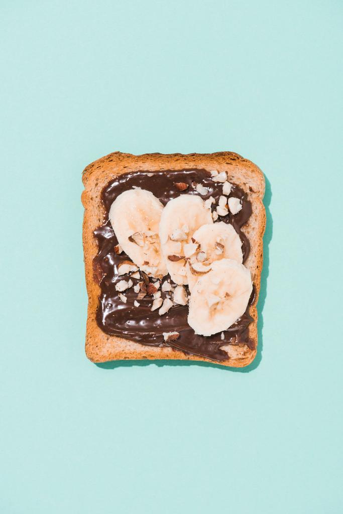 top view of delicious toast with chocolate paste and banana on blue surface - Photo, Image