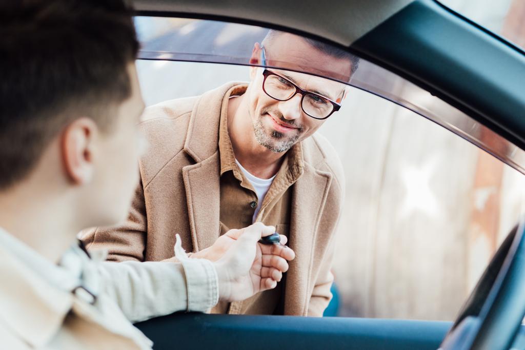 krásný veselý otec dává klíč od auta k dospívajícího syna na ulici - Fotografie, Obrázek