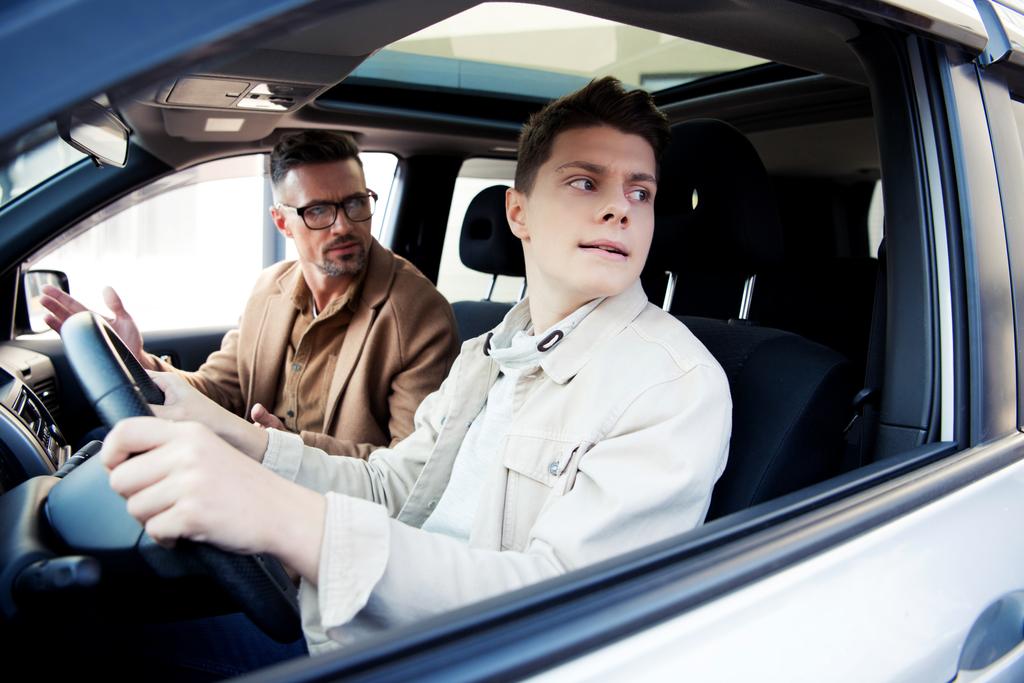 pohledný otec při pohledu na dospívajícího syna učení jedoucím autě - Fotografie, Obrázek