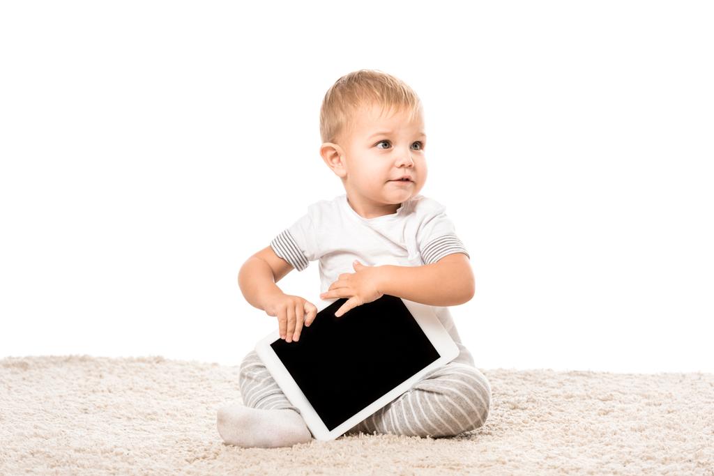 カーペットの上に座っての白で隔離デジタル タブレットを保持している素敵な幼児少年 - 写真・画像