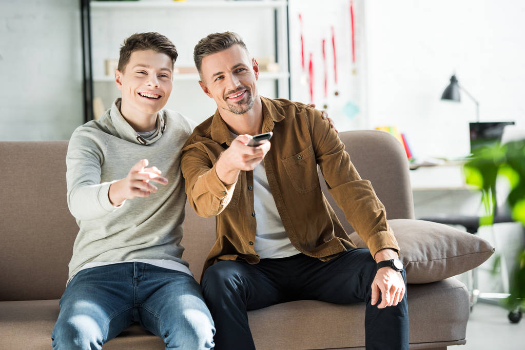 smiling father and teen son watching tv together at home - Photo, Image