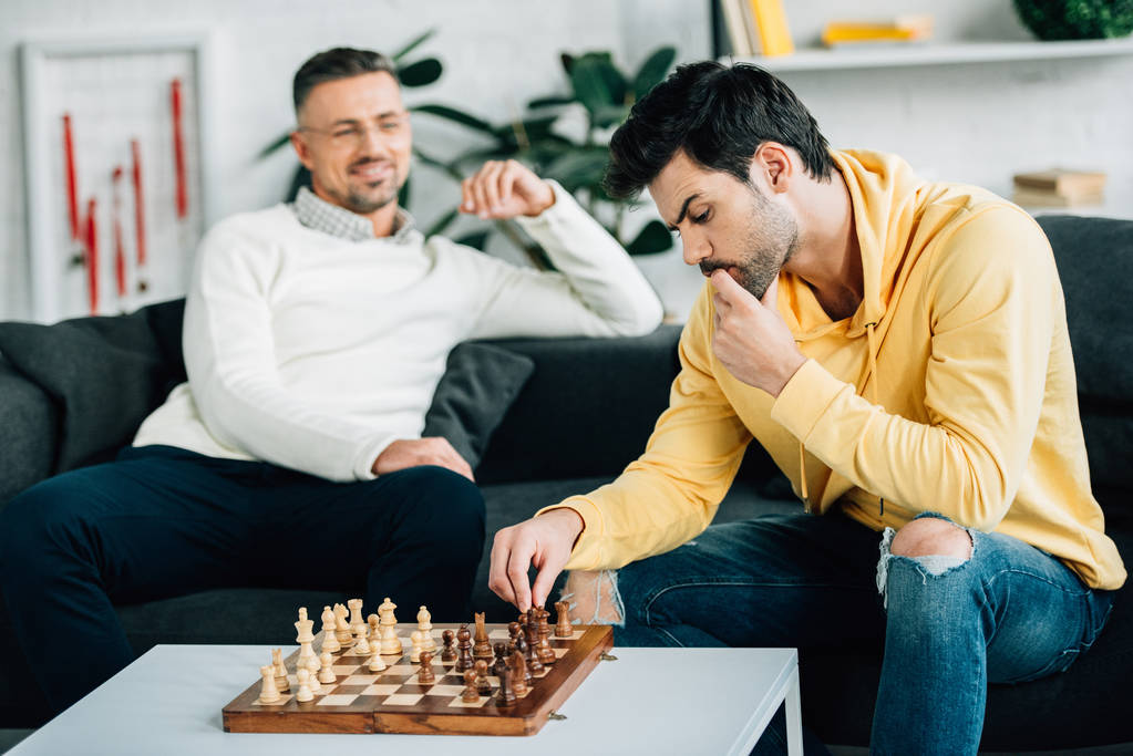 Kleiner Sohn und reifer Vater spielen am Wochenende zu Hause Schach - Foto, Bild