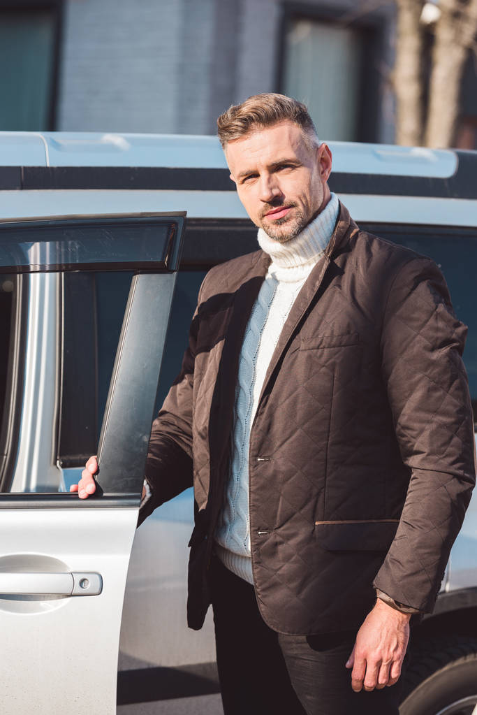 schöner Mann steht neben Auto mit geöffneter Tür  - Foto, Bild