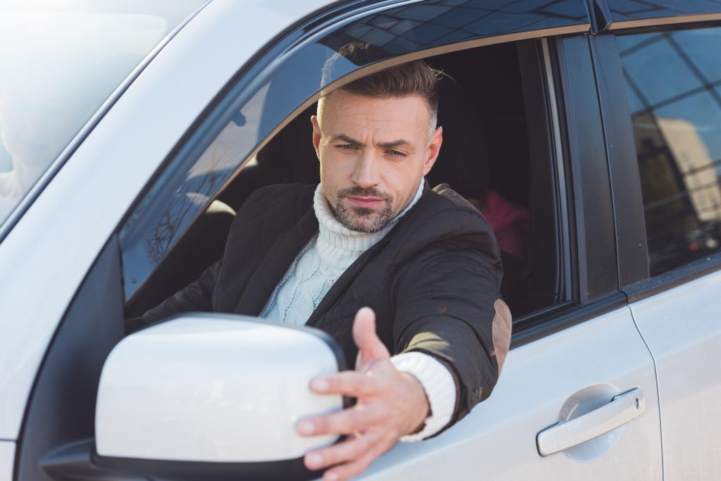 Красивый мужчина, смотрящий в зеркало и сидящий в машине
  - Фото, изображение