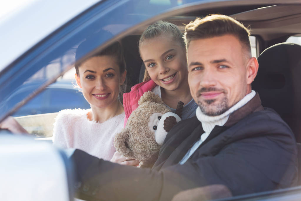  Preteen dochter zitten in auto met teddybeer, pappa en mamma - Foto, afbeelding