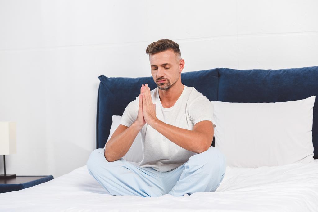 Bonito homem praticando ioga na cama
 - Foto, Imagem