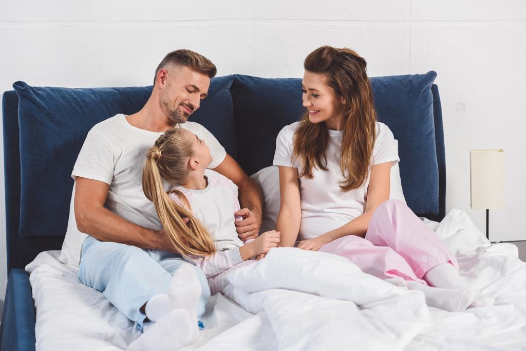 Счастливые родители улыбаются дочери в пижаме
 - Фото, изображение