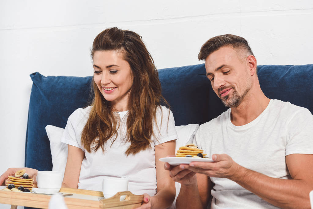 adulte sourire couple manger des crêpes dans le lit
 - Photo, image