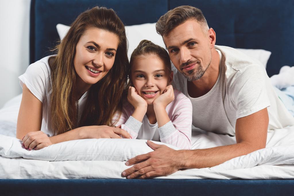 Fröhliche Familie liegt zusammen im Bett - Foto, Bild