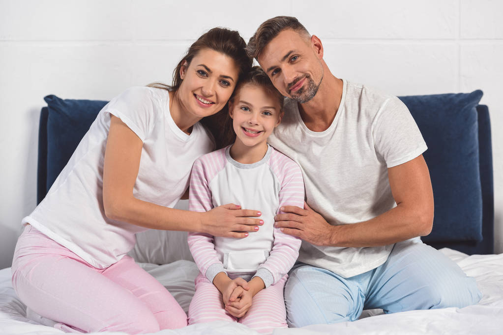 famille souriante en pyjama assis dans le lit ensemble
 - Photo, image