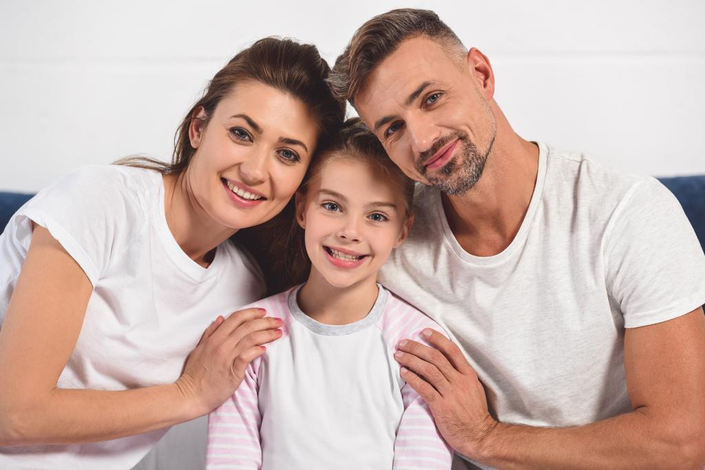 onnellinen hymyilevä vanhemmat halaavat tytär pyjama
 - Valokuva, kuva