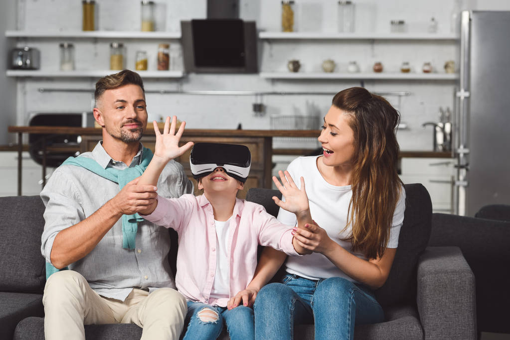 daughter sitting on sofa in virtual reality headset with parents - Photo, Image