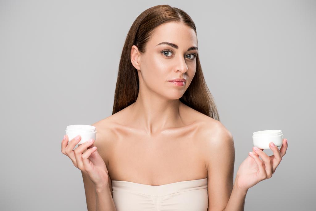 beautiful young woman choosing face cream, isolated on grey - Photo, Image