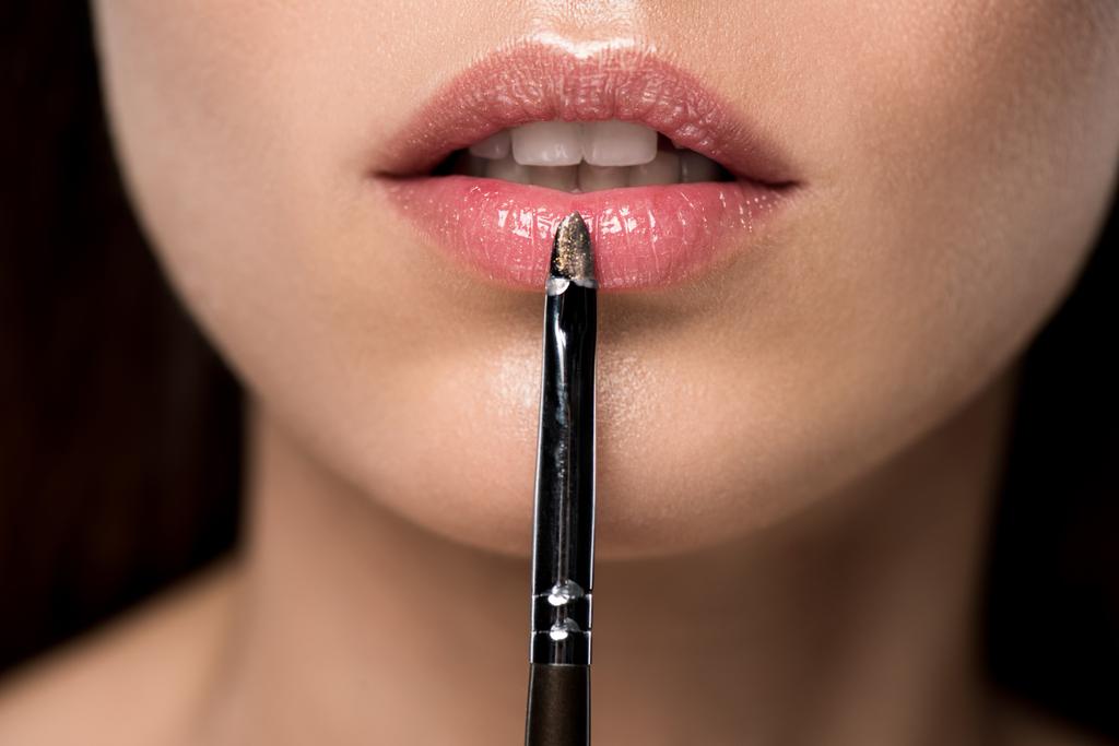weergave van meisje toepassing van lipgloss met cosmetische penseel bijgesneden - Foto, afbeelding